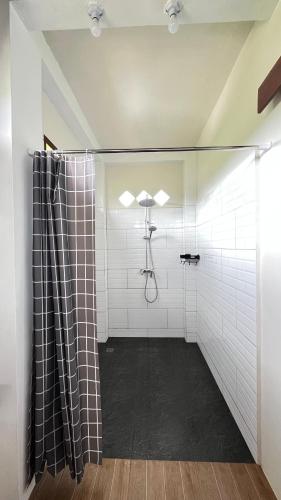 a bathroom with a shower with white tiled walls at Green Corner Villa in Bukit Lawang