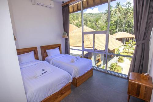 two beds in a room with a large window at Aqua Dive resort Amed in Amed