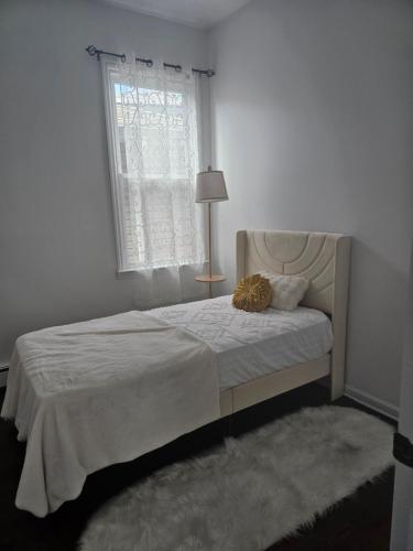 a white bedroom with a bed with a window at Cozy Getaway 2-Penn Station,NJPAC,Prudential Center in Kearny