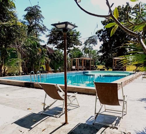duas cadeiras e um abajur em frente a uma piscina em Sala Done Khone Hotel em Ban Khon