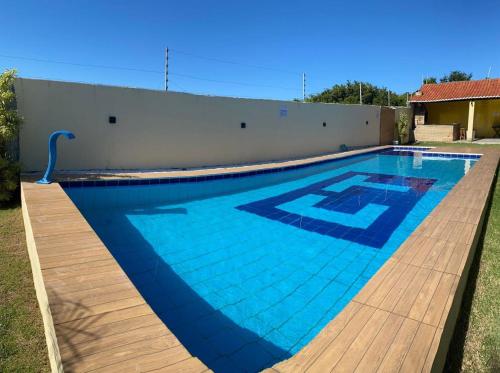 a large blue swimming pool with a wooden deck at Casa Amarela Caponga in Cascavel