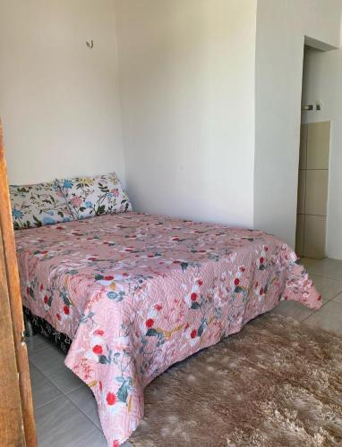 a bedroom with a bed with a pink comforter at Casa Amarela Caponga in Cascavel