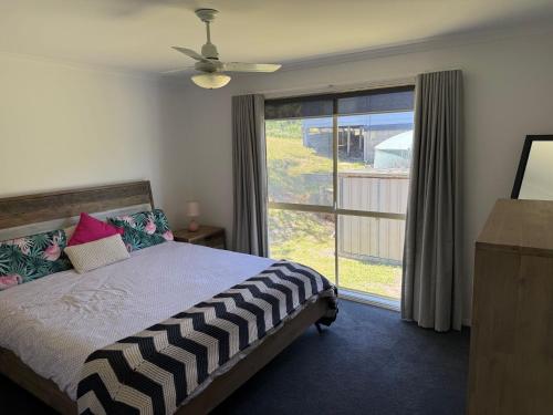 a bedroom with a bed and a large window at Famlee Ties in Venus Bay