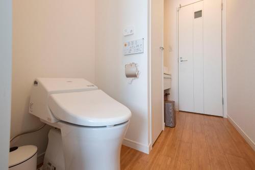 a white bathroom with a toilet and a door at kotinoma kuu in Hakozaki