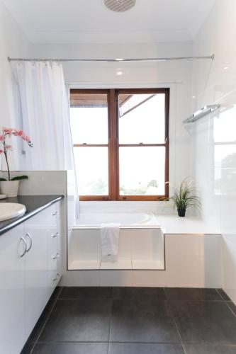 a white bathroom with a tub and a window at Toscana Village Resort in Airlie Beach