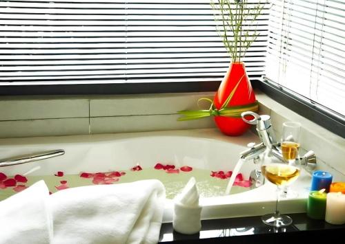 eine weiße Badewanne mit einem Glas Wein und Blumen in der Unterkunft The Sez Hotel Bangsaen in Ban Laem Thaen
