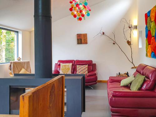 a living room with a fireplace and red couches at Glan-Y-Gors in Beddgelert