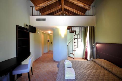 a bedroom with a bed and a tv and a staircase at Magione Papale Relais in LʼAquila