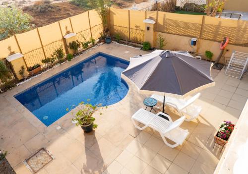 an overhead view of a pool with an umbrella and chairs at Luxury 5BR Villa with Private Pool & Lagoon Views in Ras al Khaimah