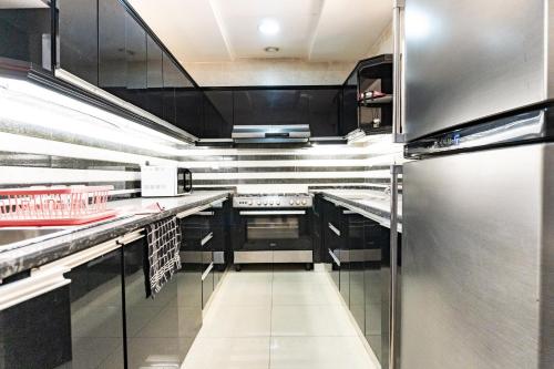 a kitchen with black cabinets and stainless steel appliances at Luxury 5BR Villa with Private Pool & Lagoon Views in Ras al Khaimah