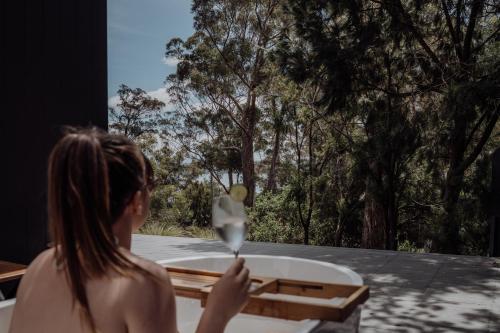 a woman is looking out a window with a spoon at Blyth Retreat, Bruny Island in Simpsons Bay
