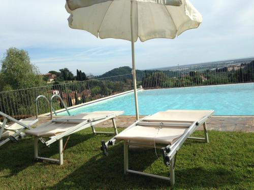 two lounge chairs and an umbrella next to a swimming pool at Lady Frantoio Toscano in Corsanico-Bargecchia