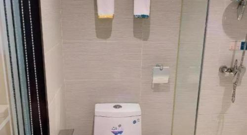 a bathroom with a toilet with a glass shower door at City Comfort Inn Zhenjiang Jurong Shimao in Jurong