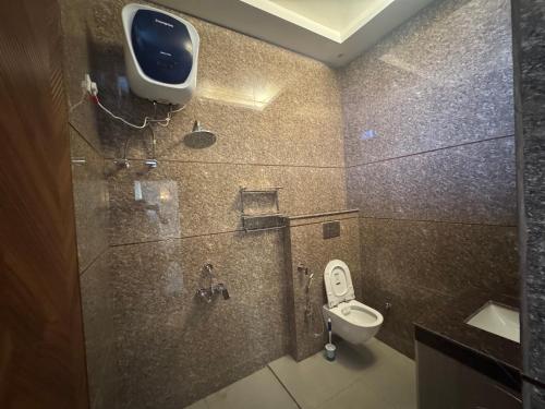 Un baño con inodoro y un televisor en la pared. en Monal by Shubhs, en Jāmb