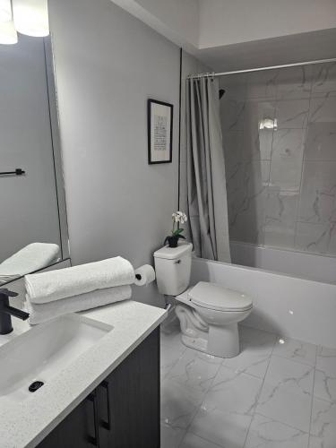 a white bathroom with a toilet and a sink at Cozy on Baywater in Airdrie