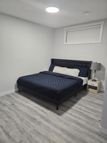 a bedroom with a black bed in a white room at Cozy on Baywater in Airdrie