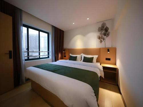 a bedroom with a large bed and a window at Green Tree Inn Guangxi Wuzhou 2nd Xinxing Road Liangguang Market in Wuzhou
