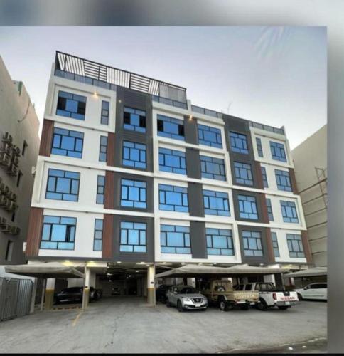 ein großes Gebäude mit auf einem Parkplatz abgestellten Autos in der Unterkunft مساكن اقتصادية in Dammam