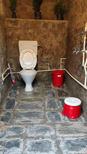 a bathroom with a toilet and two buckets at Khoj Cottage & Cafe in Dharmsāla