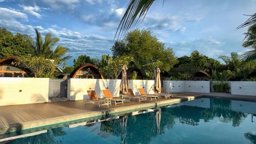a pool with chairs and umbrellas next to the water at Found Mansion Langkawi in Pantai Cenang