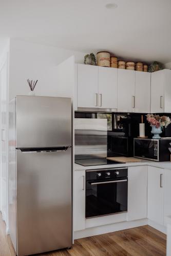 a kitchen with a stainless steel refrigerator and white cabinets at Blyth Retreat, Bruny Island in Simpsons Bay