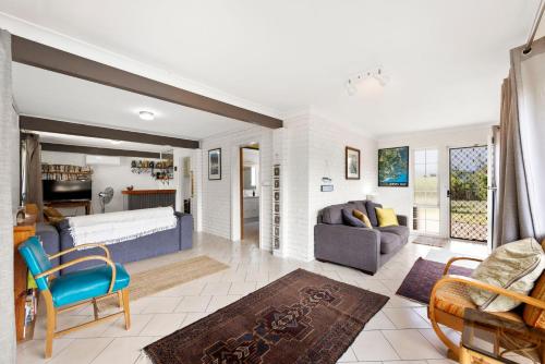 Una sala de estar con un sofá y sillas y una sala de estar en Sandpiper at Jervis Bay - Rustic Retreat, en Callala Beach