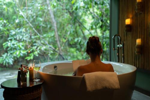 a woman sitting in a bath tub with a glass of wine at Nampien Yorla Pa in Ban Nôn