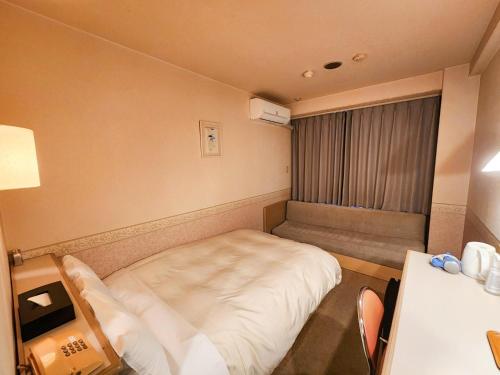 a small room with a bed and a window at Hotel Crown Hills Kanazawa in Kanazawa