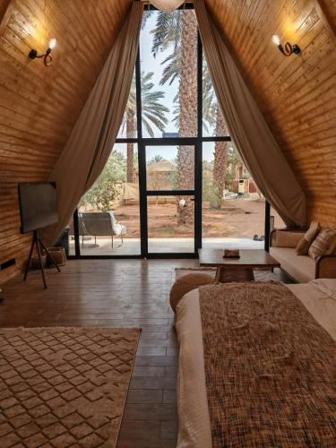 a bedroom with a large window with a couch and a tv at كوخ ساره سبيشل in Al-ʿUla
