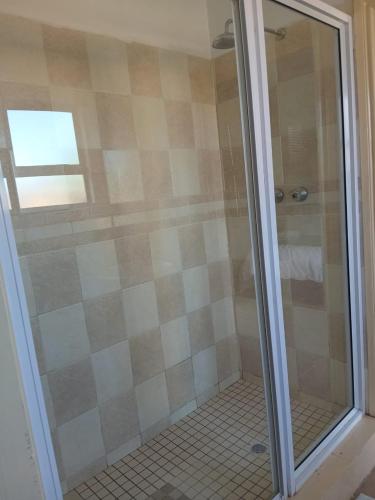 a shower with a glass door in a bathroom at Maison Royale Lodge in Nongoma