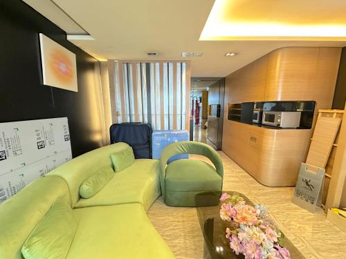 a living room with a green couch and a tv at Metacity MK 名廸旺角 in Hong Kong