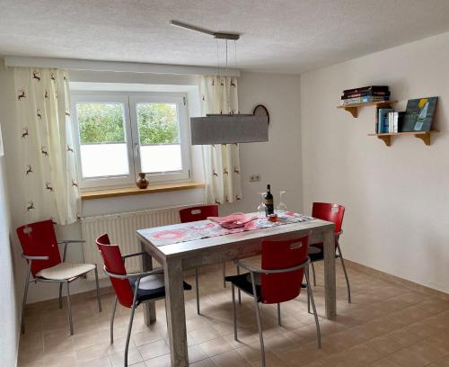 a dining room with a table and red chairs at Modern Gemütlich in Pflach
