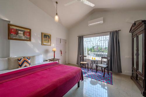 a bedroom with a large pink bed and a table at SaffronStays Brunton House - 3BR Villa with Pool & Alfresco dining in Alibaug