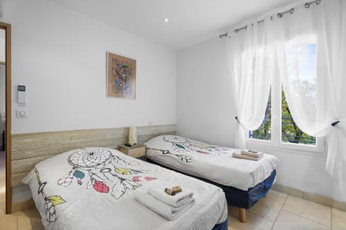two beds in a room with white walls and windows at Luxueux appartement près du port in Sanary-sur-Mer
