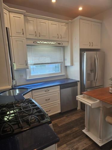 une cuisine avec des armoires blanches et un réfrigérateur dans l'établissement Cozy Getaway 3-Prudential Center, NJPAC, Penn Station, à Kearny