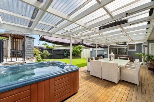 a patio with a hot tub and a table and chairs at Bayfair Break - Mt Maunganui in Mount Maunganui