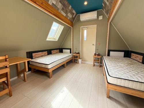 a bedroom with two beds and a table and a window at Yufuin Onsen 8A1 Yaeichi in Yufuin