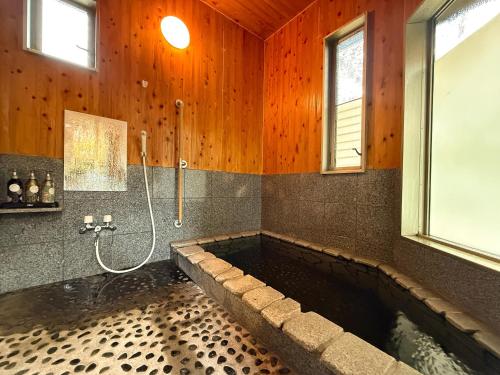 a bathroom with a large tub with a shower at Yufuin Onsen 8A1 Yaeichi in Yufuin