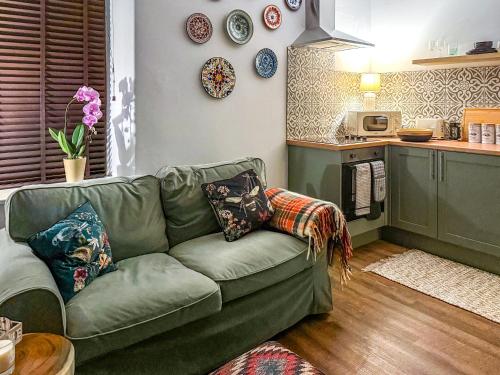 a living room with a green couch and plates on the wall at Novena - Uk50586 in Penrith