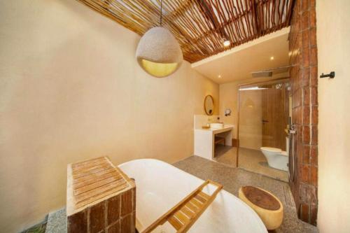 a bathroom with a tub and a sink and a toilet at Neona Spacious 4 BR Private Pool Villa ZN364 in Tanah Lot