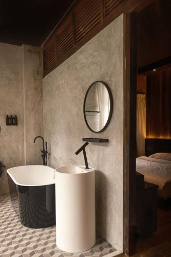 a bathroom with a tub and a mirror and a bed at Playce Hotel in George Town