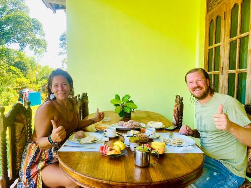 un hombre y una mujer sentados en una mesa dando pulgares hacia arriba en Hiriketiya Lima Homestay, en Dikwella