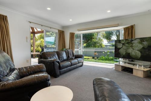 a living room with leather furniture and a flat screen tv at Bayfair Break - Mt Maunganui in Mount Maunganui