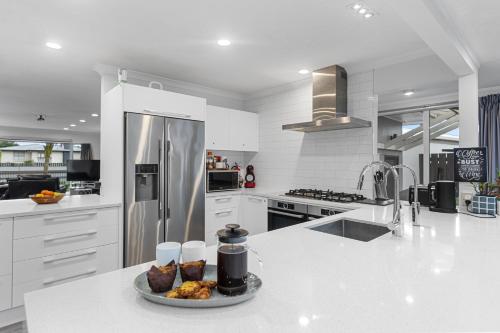 a white kitchen with a plate of food on a counter at Bayfair Break - Mt Maunganui in Mount Maunganui