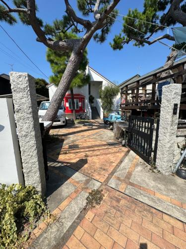 a driveway with a fence and a tree at Guest Room Chigasaki in Chigasaki