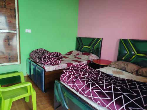 due letti in una stanza con una parete verde di Shri Ganesh Home stay a Ukhimath