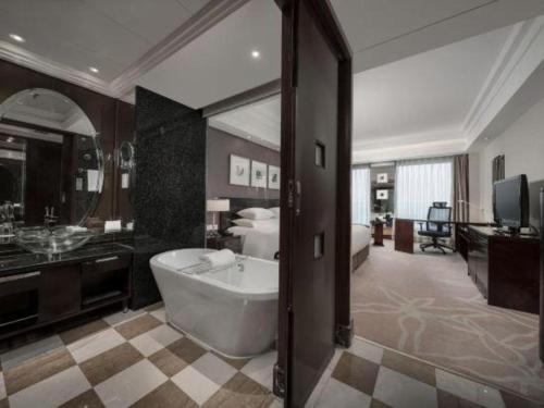 un ampio bagno con vasca e una camera da letto di New Century Hangzhou Grand Hotel a Xiaoshan