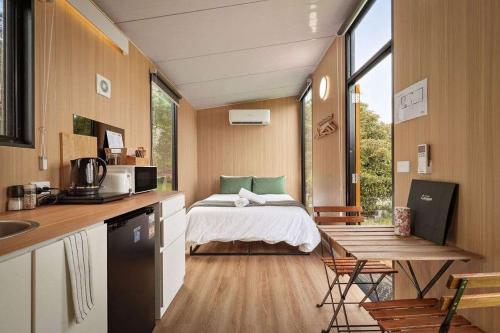 a room with a bed and a kitchen with a table at Lazy Daisy Farm by Tiny Away in Warragul