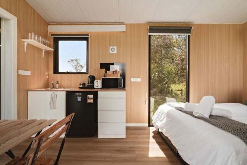 a bedroom with a bed and a kitchen with a table at Lazy Daisy Farm by Tiny Away in Warragul