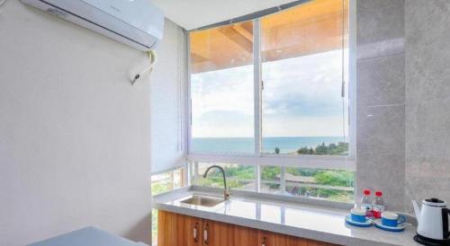 a kitchen with a window with a view of the ocean at Kingreal seaview resort sanya in Sanya